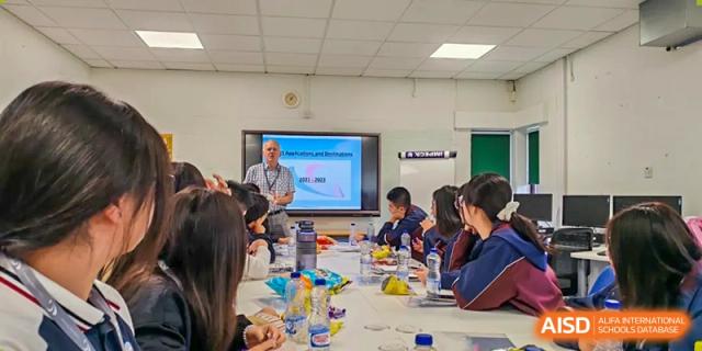 Zhejiang Wenzhou High School International Division students and staff attending a formal presentation in a meeting room, focused on a screen at the front.
