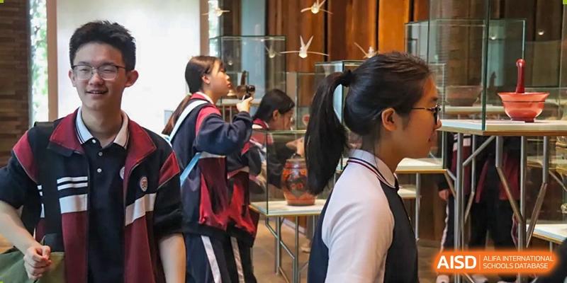 Zhejiang Wenzhou High School International Division students in school uniforms looking at exhibits, such as hanging paper cranes, in a museum or gallery.