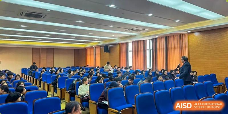 A large group of Zhejiang Wenzhou High School International Division students attending a lecture or presentation in a tiered auditorium with blue seats.