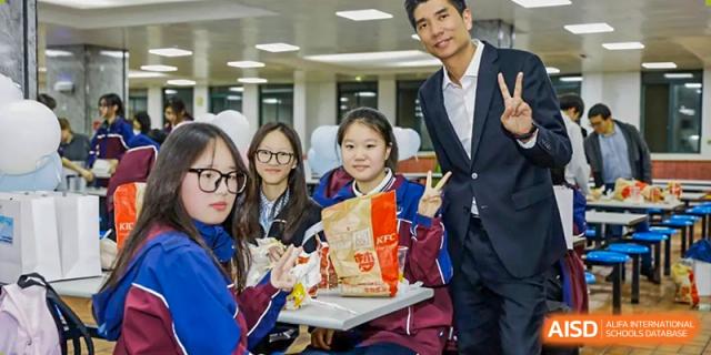 A group of Zhejiang Wenzhou High School International Division students in casual wear posing happily with their food, likely during a meal break at school.