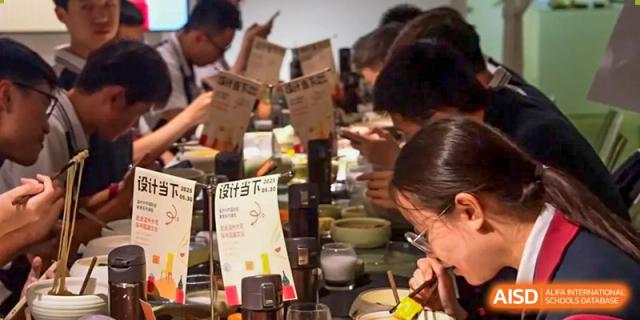 Zhejiang Wenzhou High School International Division students gathered around a food counter, looking at menus and selecting items during a busy mealtime.