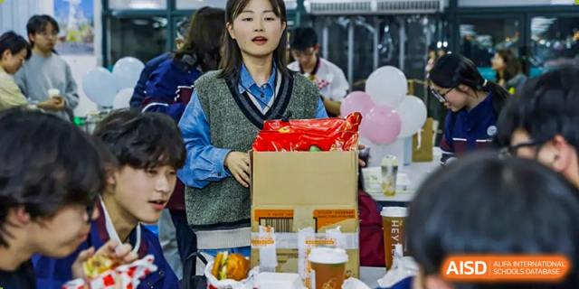 A female student from Zhejiang Wenzhou High School International Division handling a box and cups of drinks for an event or party delivery.