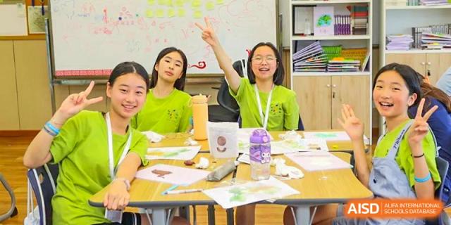 A student from YK Pao School raising her hand to answer a question in a classroom.