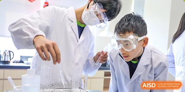 Two students from YK Pao School wearing safety goggles and working on a science experiment in a lab.