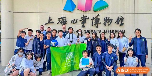 A group of students and teachers from YK Pao School holding a banner at the Shanghai Children's Expo.