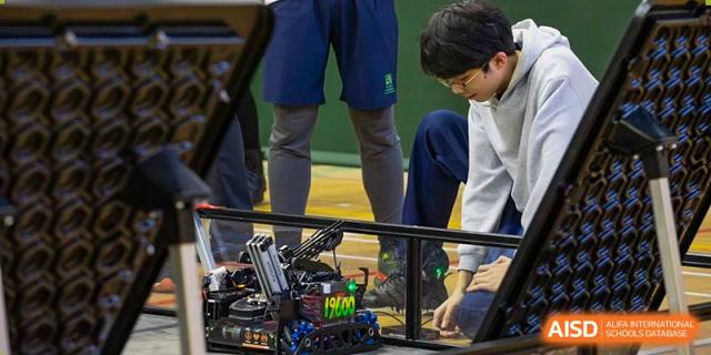 Students from YK Pao School kneeling to work on a small robot.