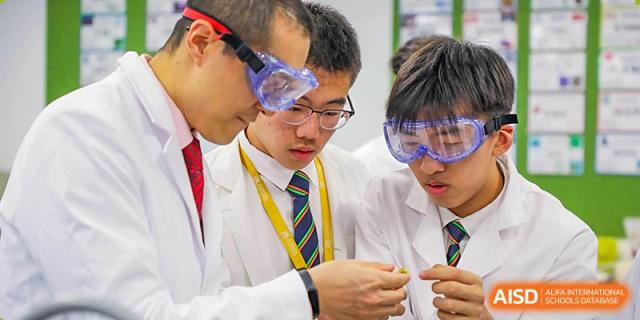 Students and a teacher from YK Pao School working together on a project, with a student wearing safety goggles.