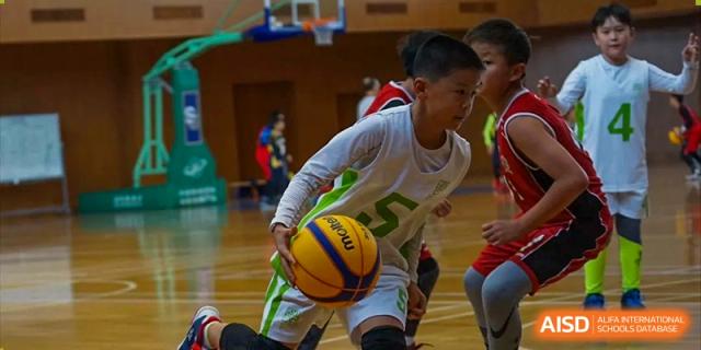 A young male student from YK Pao School dribbling a basketball on a court.