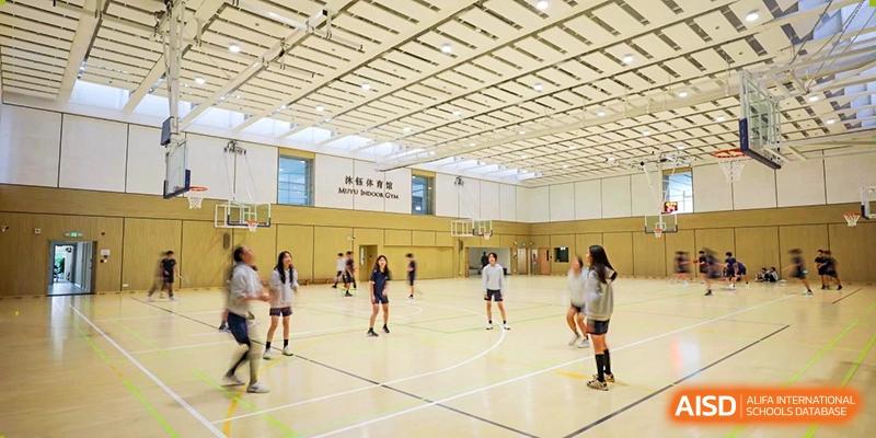 A group of students from YK Pao School playing volleyball in a gymnasium.