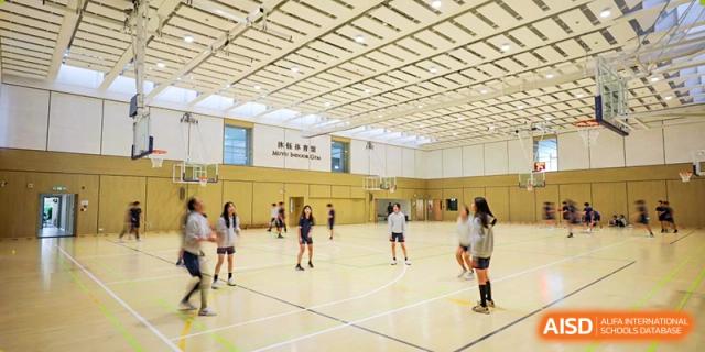 A group of students from YK Pao School playing volleyball in a gymnasium.