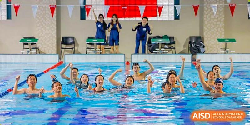 Students and a teacher from YK Pao School posing for a photo in a swimming pool.