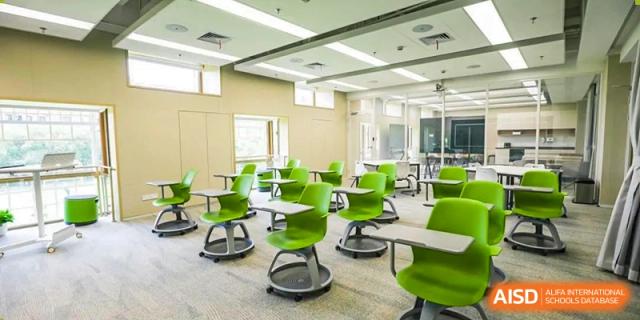 A bright, modern classroom at YK Pao School with green chairs and mobile desks.