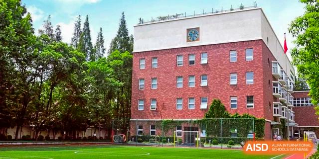 A close-up exterior shot of a red brick building at YK Pao School with a clock tower and a green lawn.
