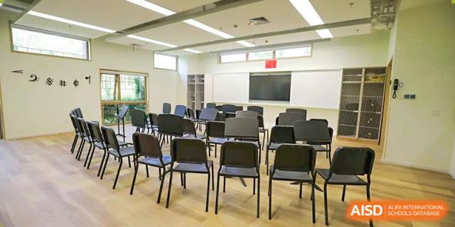 An empty lecture or meeting room at YK Pao School with rows of chairs facing a projector screen.