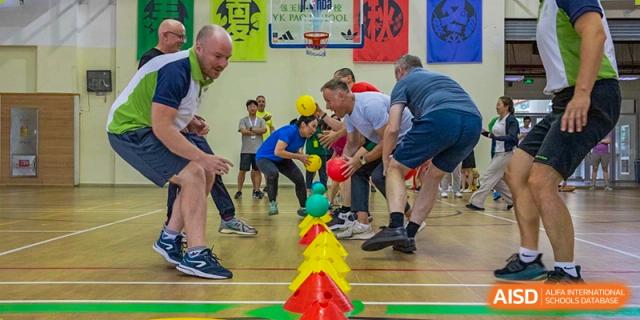 Students and a teacher from YK Pao School participating in an outdoor sports activity with colorful cones.