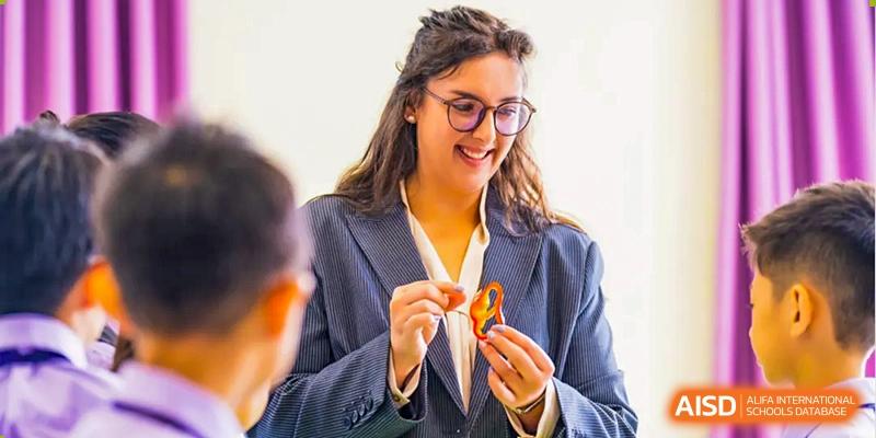 A female teacher with glasses holds a paper crane. Guangzhou International Primary/Middle School Huangpu