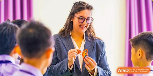A female teacher with glasses holds a paper crane. Guangzhou International Primary/Middle School Huangpu