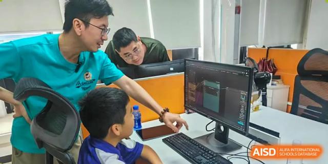 A male student points to a computer screen while a teacher looks on. Guangzhou International Primary/Middle School Huangpu