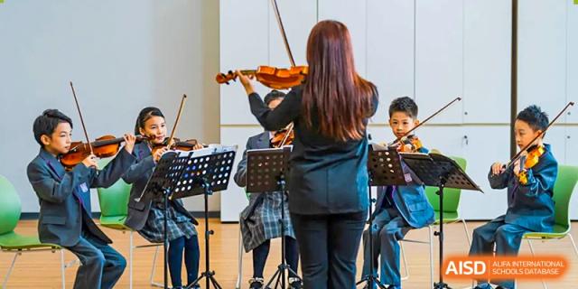A girl with long red hair plays the violin on a stage. Guangzhou International Primary/Middle School Huangpu