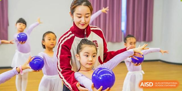 A dance teacher with a young student holding a purple ball. Guangzhou International Primary/Middle School Huangpu