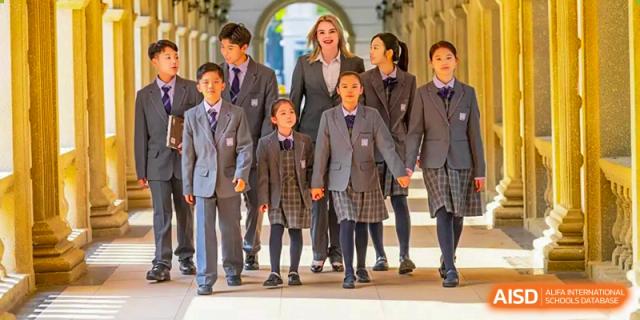A teacher and three students in gray uniforms pose for a photo. Guangzhou International Primary/Middle School Huangpu
