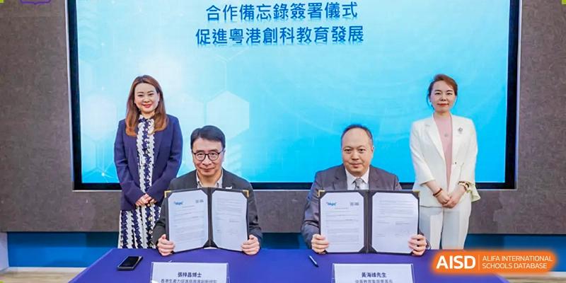Two men in suits shake hands while holding a signed document. Guangzhou International Primary/Middle School Huangpu