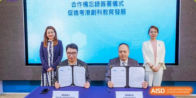 Two men in suits shake hands while holding a signed document. Guangzhou International Primary/Middle School Huangpu