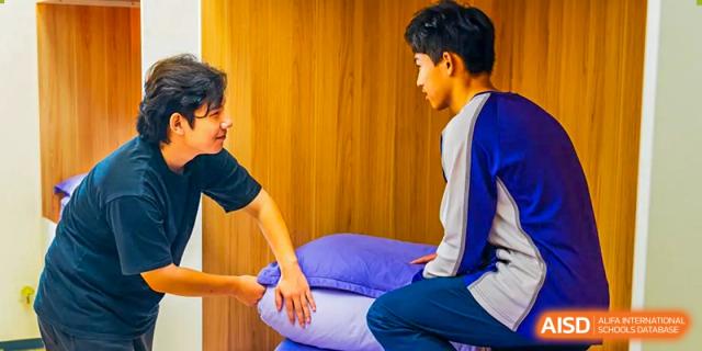 A student in a blue uniform receives a back massage on a purple pillow. Guangzhou International Primary/Middle School Huangpu