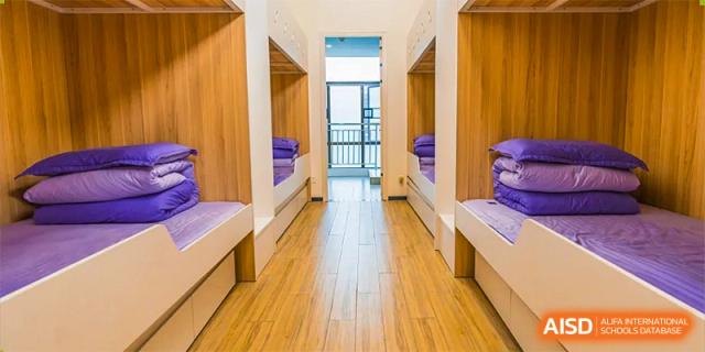 The inside of a clean dormitory room with two bunk beds and a wooden floor. Guangzhou International Primary/Middle School Huangpu