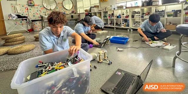 Hands-on learning at Zhuhai Qiao International School with students working on a robotics or building project with various parts and a laptop nearby.
