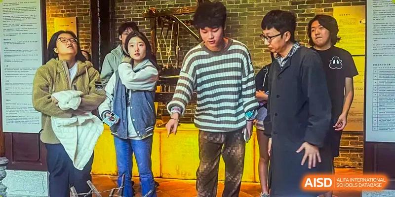 A group of older students from Zhuhai Qiao International School standing together in a casual setting during a school trip or event.