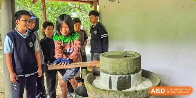 Students from Zhuhai Qiao International School on a field trip, learning to operate a traditional stone grinding mill.