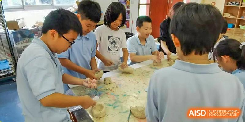 A small group of students at Zhuhai Qiao International School collaborating on a hands-on art project, sculpting with clay or dough.