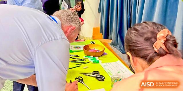 A close-up of a table at Zhuhai Qiao International School during an arts and crafts activity with scissors, beads, and green felt materials.