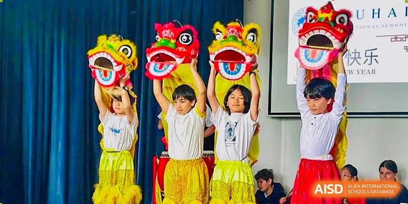 Students at Zhuhai Qiao International School performing a traditional Chinese lion dance for a cultural celebration or event.