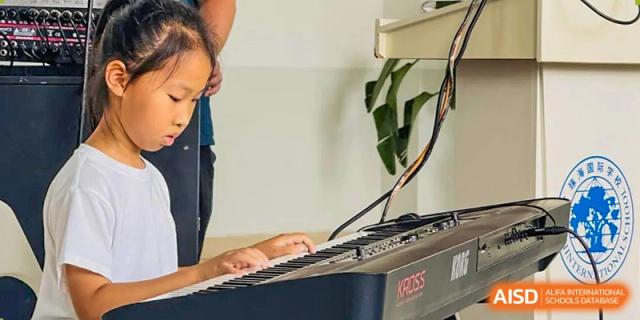A close-up of a student at Zhuhai Qiao International School practicing on a keyboard or digital piano during a music lesson.