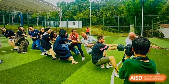Zhuhai Qiao International School students participating in a team-building tug-of-war game outdoors.