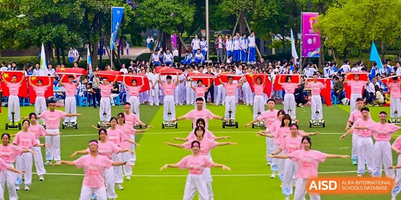 Aerial view of a mass performance by Chengdu No.7 High School International Department students in pink outfits performing on a field with red ground cover.