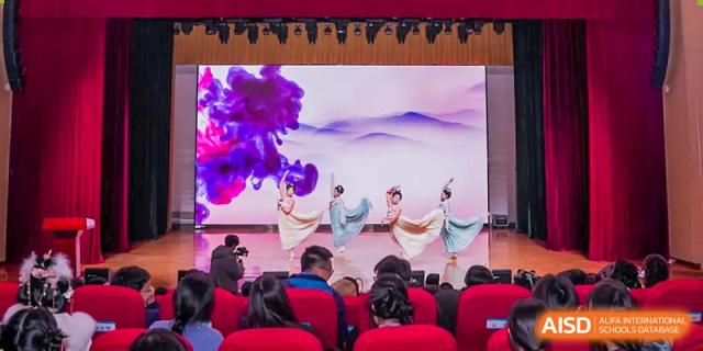 Chengdu No.7 High School International Department students performing a traditional dance on stage with a flowing, artistic backdrop.