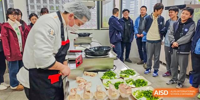 Chengdu No.7 High School International Department students or staff preparing food, possibly dumplings or pastries, in a practical cooking area.