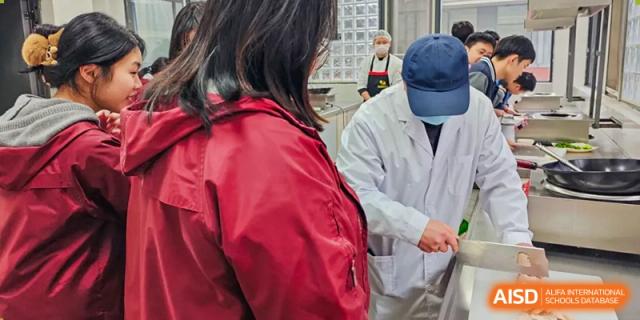 Chengdu No.7 High School International Department student or staff member in a lab coat receiving instruction during a health or food safety activity.