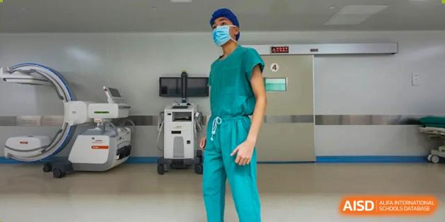 A Chengdu Shishi High School Cambridge A-Level Centre student wearing scrubs and a mask in a lab or medical setting.