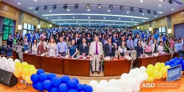 Chengdu Shishi High School Cambridge A-Level Centre faculty and students on a stage in front of a large audience at a school event.