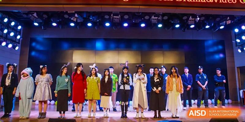 A group of well-dressed adults and Chengdu Shishi High School Cambridge A-Level Centre students stand on a stage.