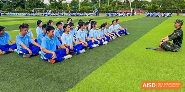 Chengdu Shishi High School Cambridge A-Level Centre students sit on a grassy field and watch a game.