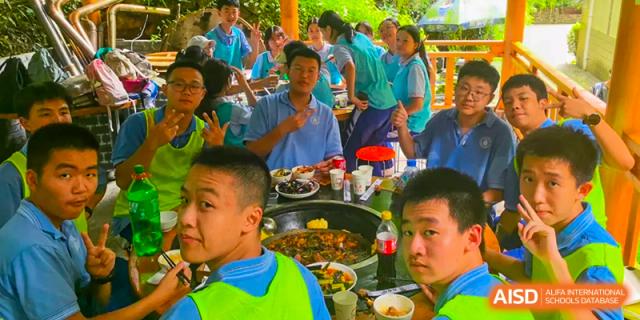 A group of Chengdu Shishi High School Cambridge A-Level Centre students at a meal, with one student looking at the camera.
