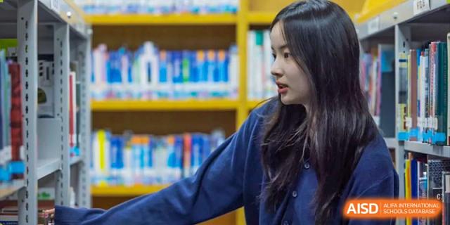A Concordia International School Shanghai student looking towards the front of a library or learning center with colorful bookshelves behind her.