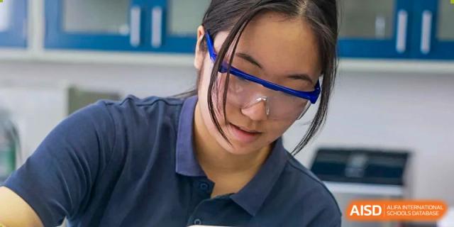 A female student from Concordia International School Shanghai wearing safety goggles and concentrating on a task in a science class.