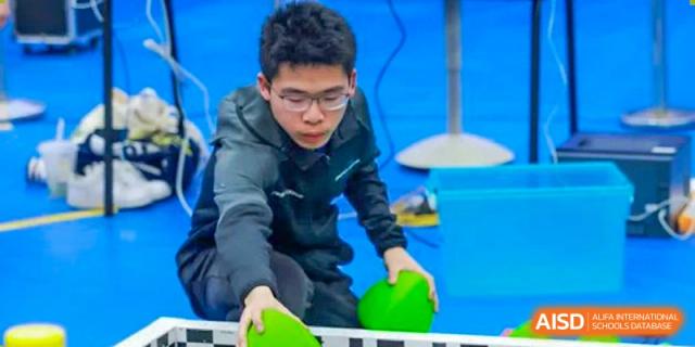 A male student from Concordia International School Shanghai wearing safety glasses and working on a hands-on project with green plastic components.