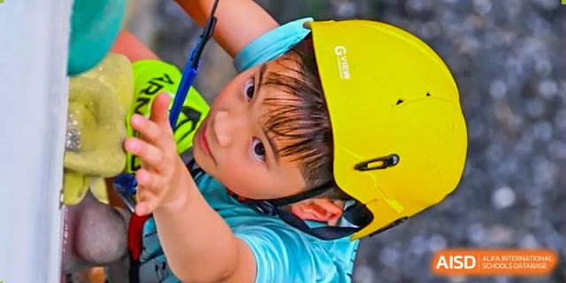 A young student from Concordia International School Shanghai wearing a yellow helmet and looking up during an outdoor activity.